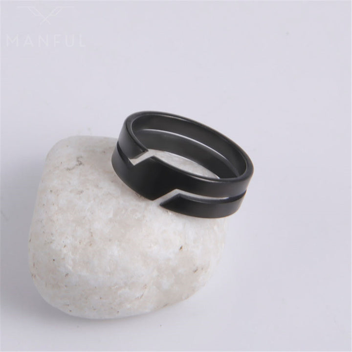 Line Cut Ring Black, propped against a white pebble