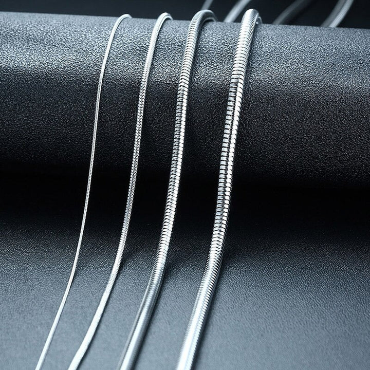 Snake Chain 3mm Silver, four chains draped over a black stone prop