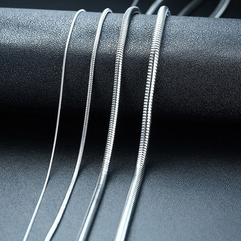 Snake Chain 2mm Silver, four chains draped over a black stone prop