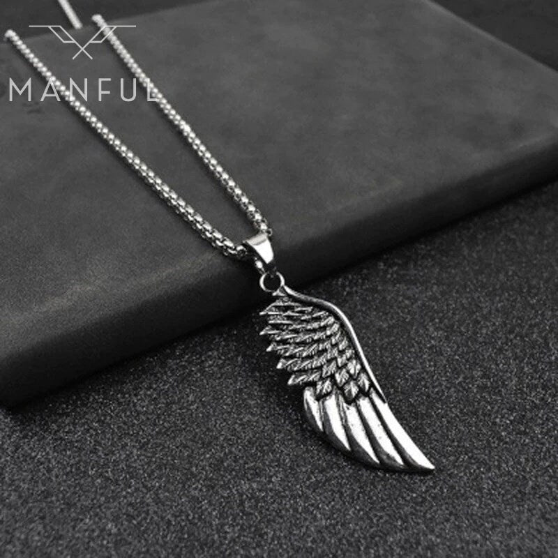 Wing Pendant Necklace, laid flat across the edge of a grey stone block
