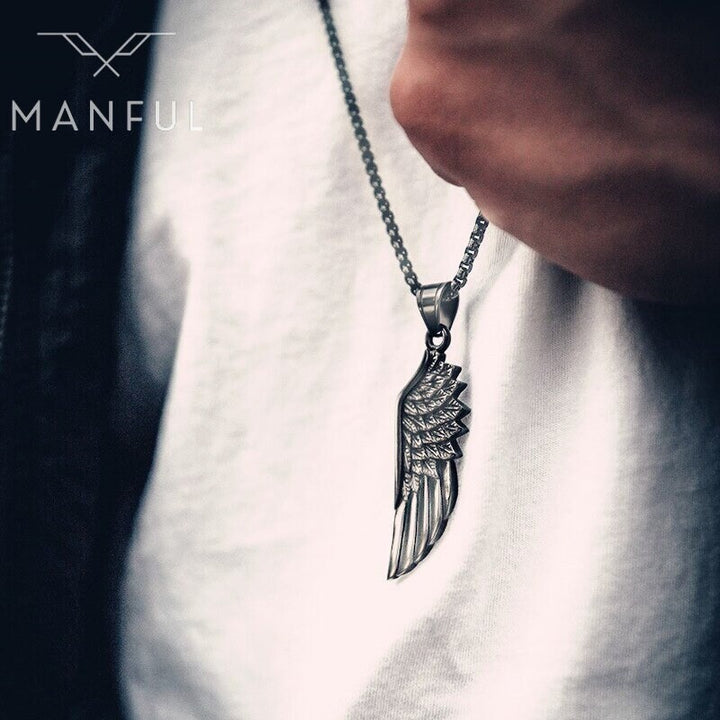 Wing Pendant Necklace, worn at the collar of a white t-shirt, held between fingers